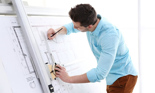 Architect stood using large drawings board to draw up plans